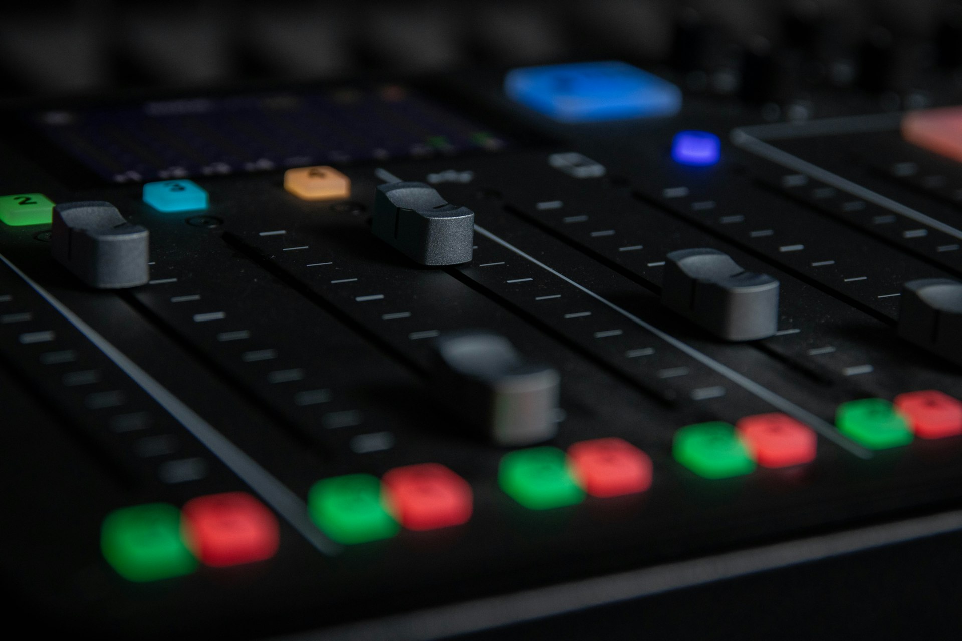 Close-up of FOH mixing console faders in low light